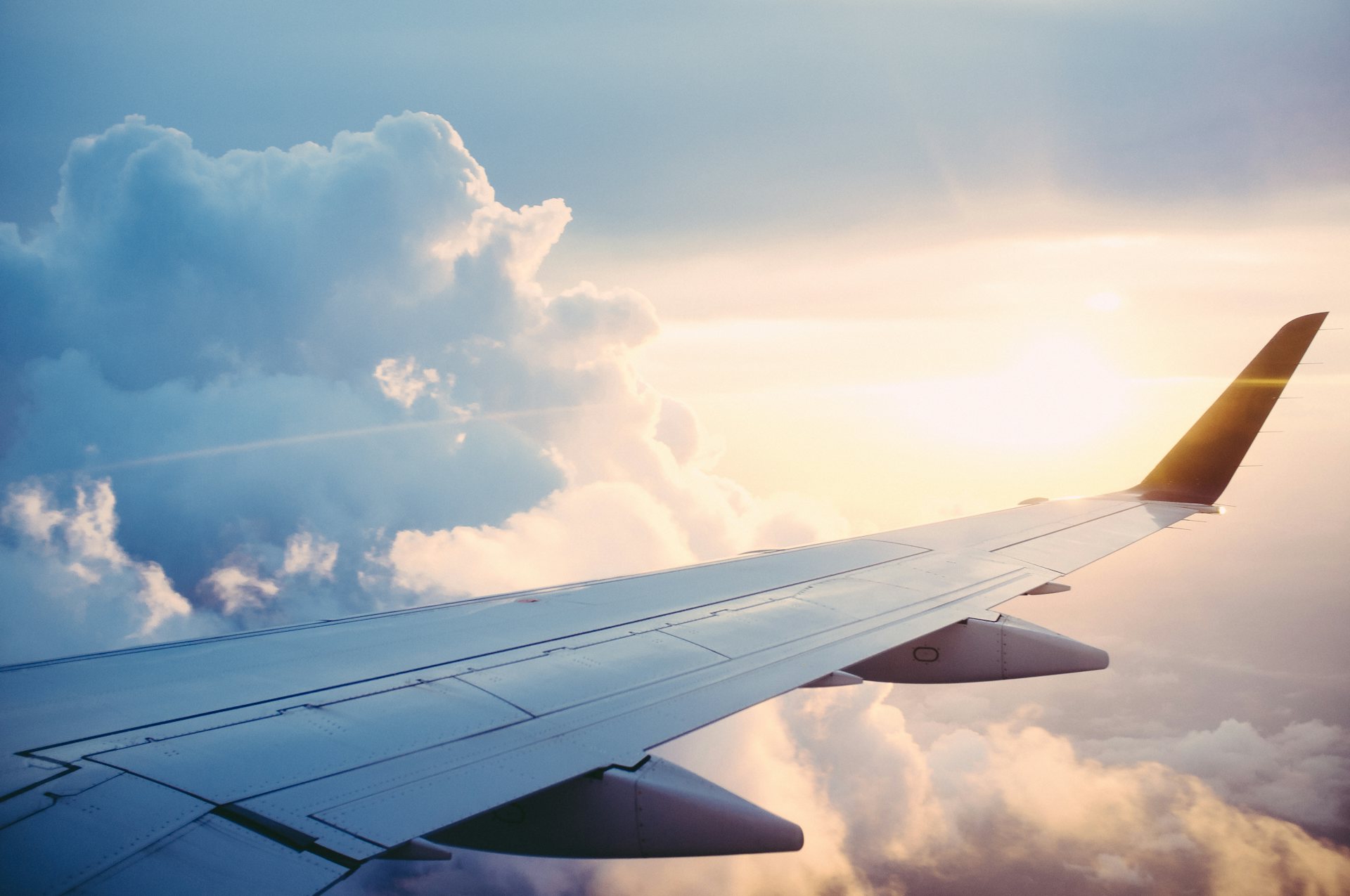 Vue d'une aile d'avion au-dessus des nuages, au coucher du soleil